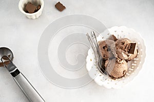 Three brown chocolate ice cream balls, scoops in white bowl on gray background, copy space. Top view