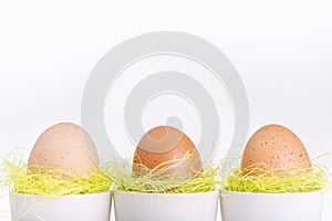 Three brown eggs in white cups