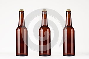 Three brown longneck beer bottle 330ml mock up. Template on white wood table. photo