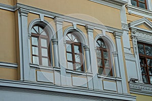 Three brown windows on the concrete wall of the building