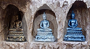 three buddha statues in niches made out of rocks together