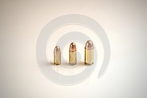 Three bullets of different calibers on a white surface.