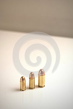 Three bullets of different calibers on a white surface.