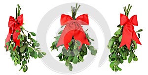 Three bunches of fresh green mistletoe tied with bright red Christmas bows. Isolated on white