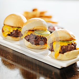 Three burger sliders with cheese and pickle