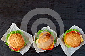 Three burgers with falafel, salad, onion rings, cheese and tomatoes on the black background. Traditional Middle Eastern fast food
