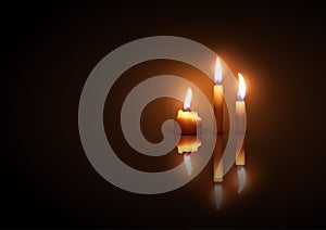 Three burning candles on a dark background with reflection effe