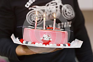 Three burning candles on the pink bithday cake