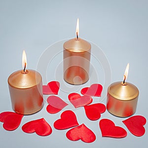 Three burning candles with scarlet hearts