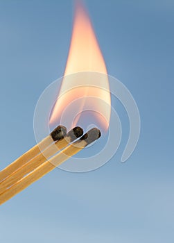 Three burning matches on a blue background