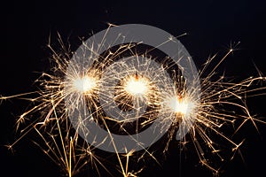 Three burning New year sparklers on black background