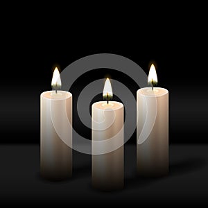 Three burning realistic pillar candle on black background