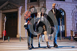 Three business colleagues enjoying a lively conversation while crossing the street in an illuminated urban setting after