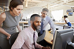 Three business colleagues working together around a monitor