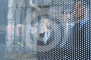 Three business people behind a glass wall looking out, unrecognizable faces