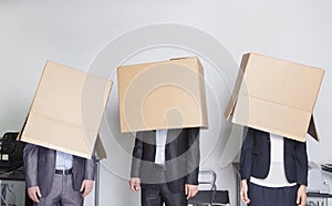 Three business people with boxes over their heads in an office