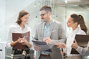 Three business people discussing documents during a meeting in office.