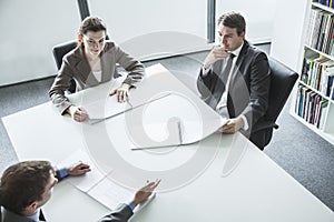 Three business people sitting around a table and having a business meeting, high angle view photo