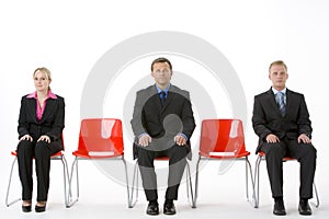 Three Business People Sitting On Red Plastic Seats