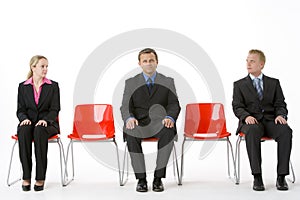 Three Business People Sitting On Red Plastic Seats