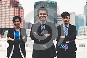 Three business people standing with arms crossed.