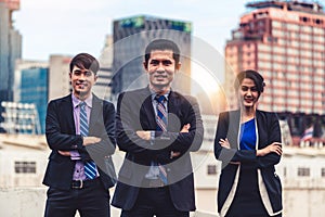 Three business people standing with arms crossed.