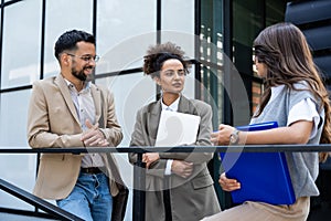 Three business people waiting in front of office building taking a break, before staff meeting. Lawyers and law students on