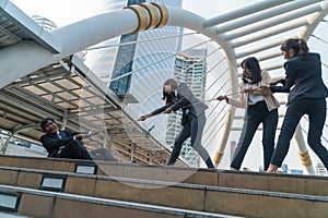 Three business women and middle-aged businessmen playing tug-of-war