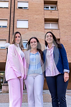 Three business women are standing in front of a buildin