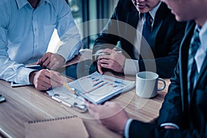 Three businessman looking at graph in paper and talk about business plan, marketing and financial in the future.