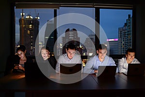 Three businessman and two businesswoman working with computer overtime at night