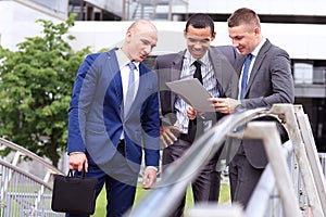 Three Businessmen Discussing Document Outside Office
