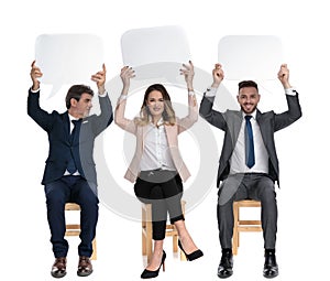 Three businessmen holding speech bubble above their heads