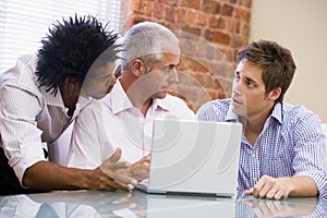 Three businessmen in office with laptop