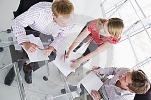 Three businesspeople in boardroom with paperwork