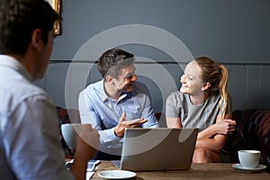 Three Businesspeople Having Meeting In Cafe