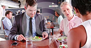 Three Businesspeople Having Working Lunch In Restaurant