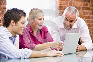 Three businesspeople in office with laptop