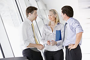 Three businesspeople standing in corridor talking