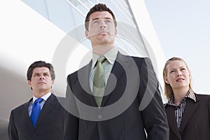 Three businesspeople standing outdoors by building