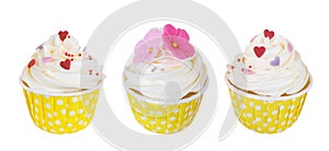 Three butter cream cupcakes with sweet flowers and hearts in polka dot paper cup isolated on white background, path