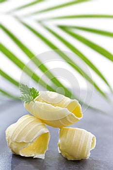 Three Butter curl or roll, front view.greenery in the background