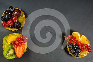Three cakes with fresh bio fruits, orange, kiwi, strawberries, blueberries, red currants, grapes, raspberries, blackberries, photo