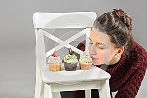 Three cakes stand on white chair, young girl bent photo