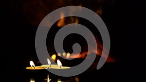 Three candles on a black background with a fireplace flame.