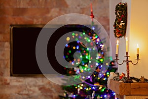 Three candles are burning in dark room behind Christmas tree