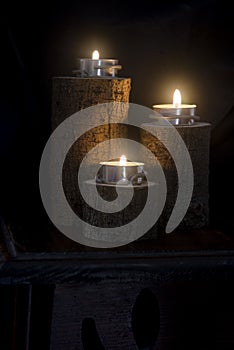 Three candles lit in wooden candlesticks