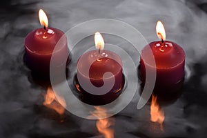 Three candles reflecting in water