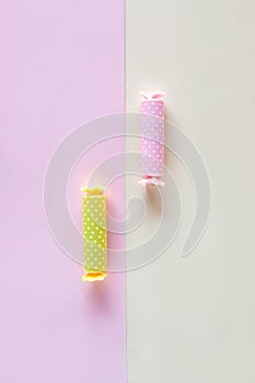 Three candy in polca dot wrapper on pink background