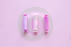 Three candy in polca dot wrapper on pink background